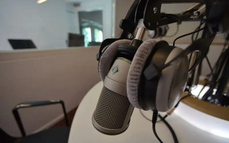 Microfone de estúdio sobre mesa, com fones de ouvido ao lado
