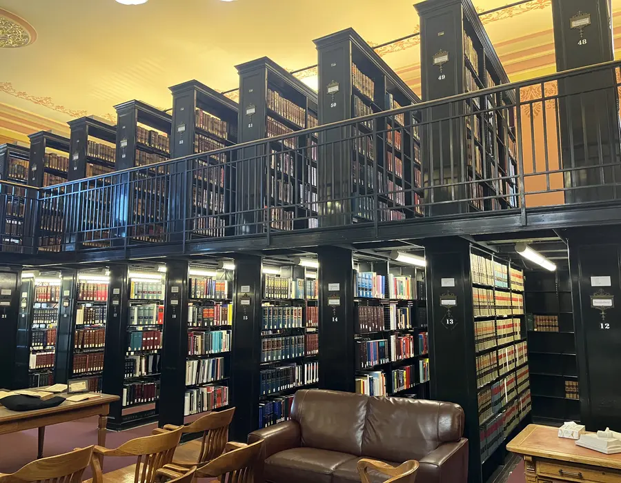 Estantes de biblioteca cheias de livros, com mesas de leitura