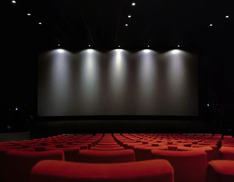 Sala de cinema com poltronas escuras e tela ao fundo